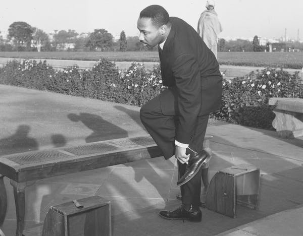 Rev. Martin Luther King Jr. removes his shoes before entering Mahatma Gandhi’s shrine in New Delhi, India, on Feb. 11, 1959. AP Photo