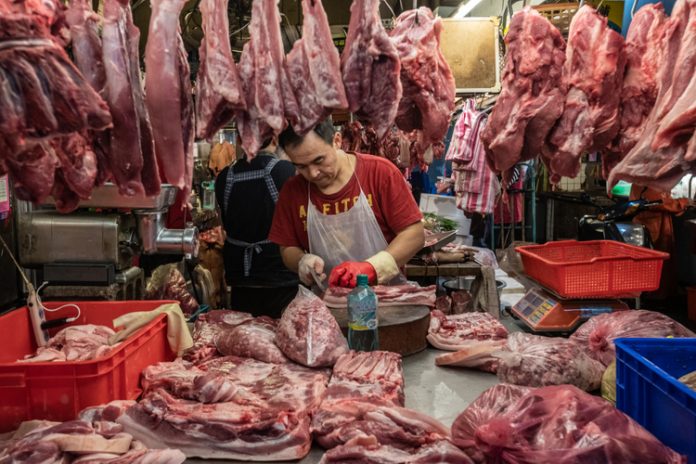 Vendor chops slabs of meat and hangs them for sale at a wet market in Taipei.