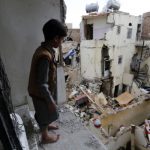 A Yemeni child looks at the ruins of war from a dilapidate structure