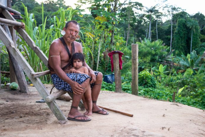 An indigenous man and child featured in the documentary. Image by Michael Clark/Gravitas Ventures.