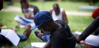 An unaccompanied foreign minor does lessons provided by a volunteer in a park in Toulouse, France, October 2017. Alain Pitton/NurPhoto via Getty Images