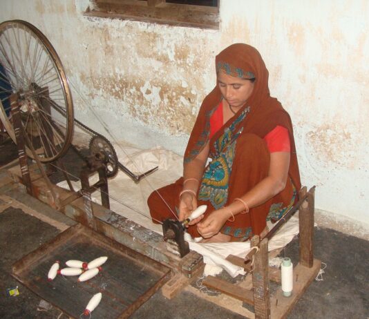 A lady using a spinning wheel to make coarse cotton thread/ Image:Pixabay